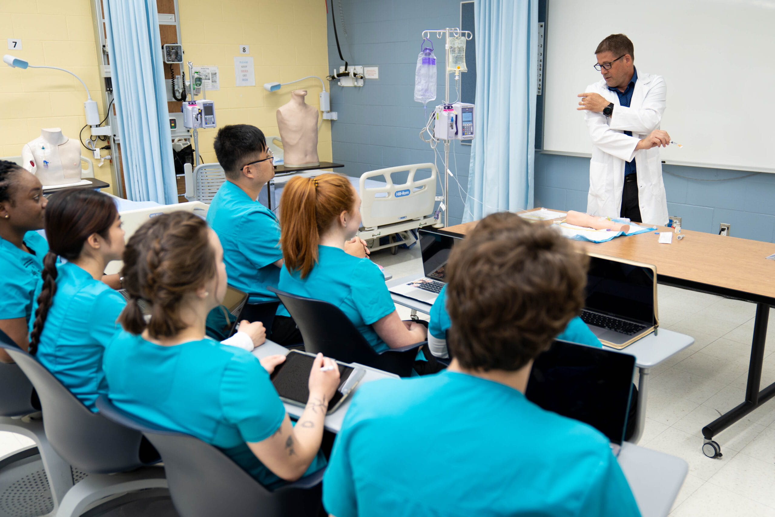 nursing students in a classroom attentively listening to their instructor