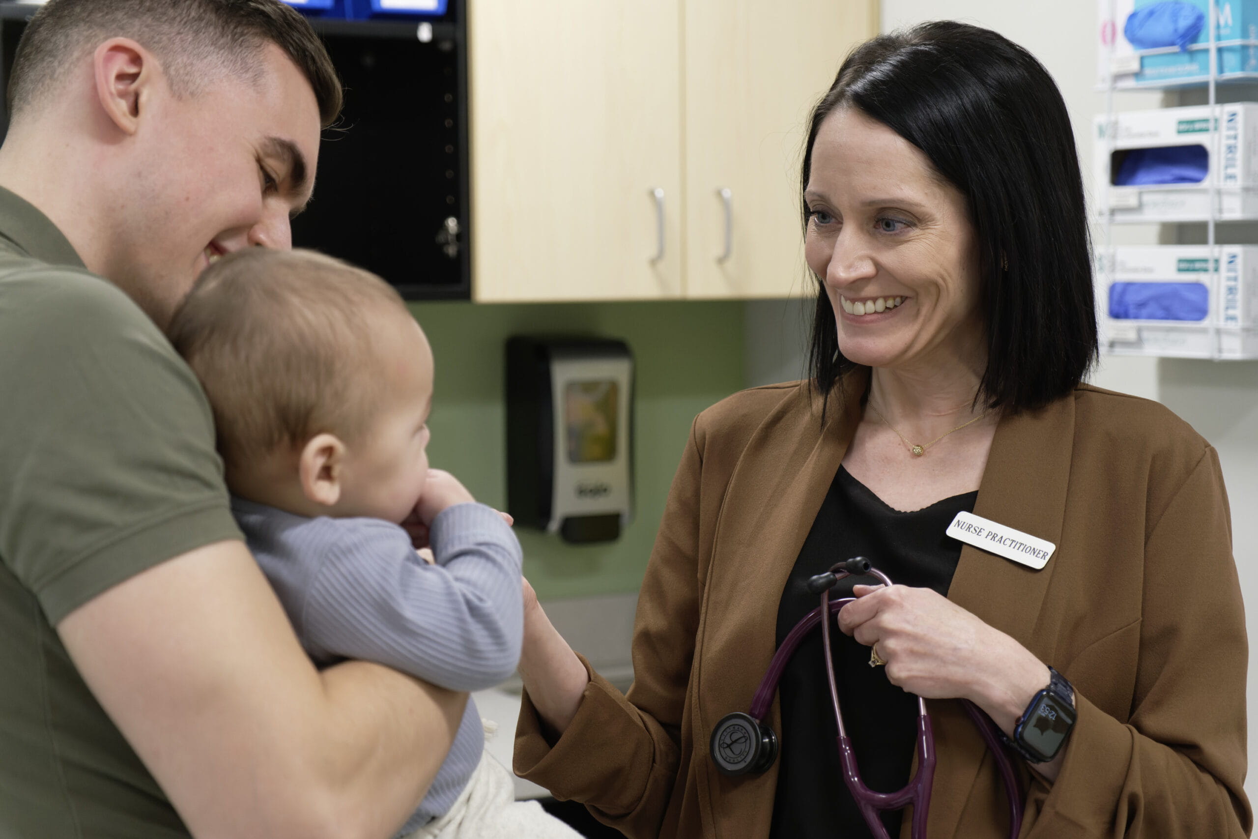 female nurse practitioner interacting with a father holding an infant